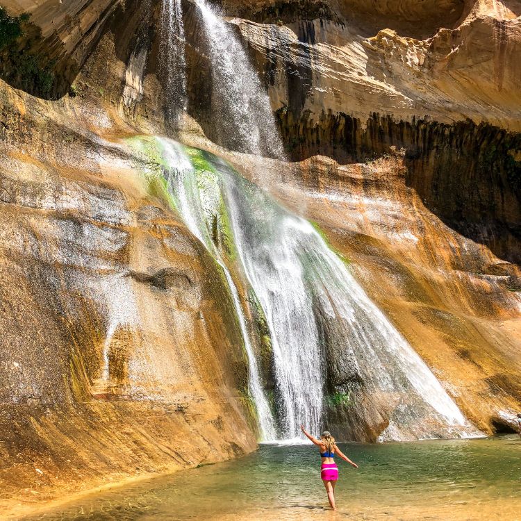 Woman playing in Lower Calf Creek Falls in Utah.