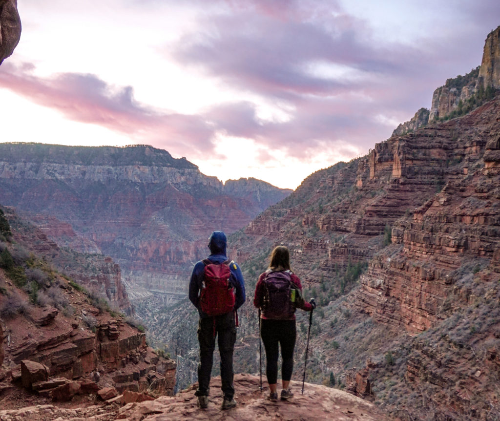 Man and woman hiking Rim to Rim in the Grand Canyon at sunrise.