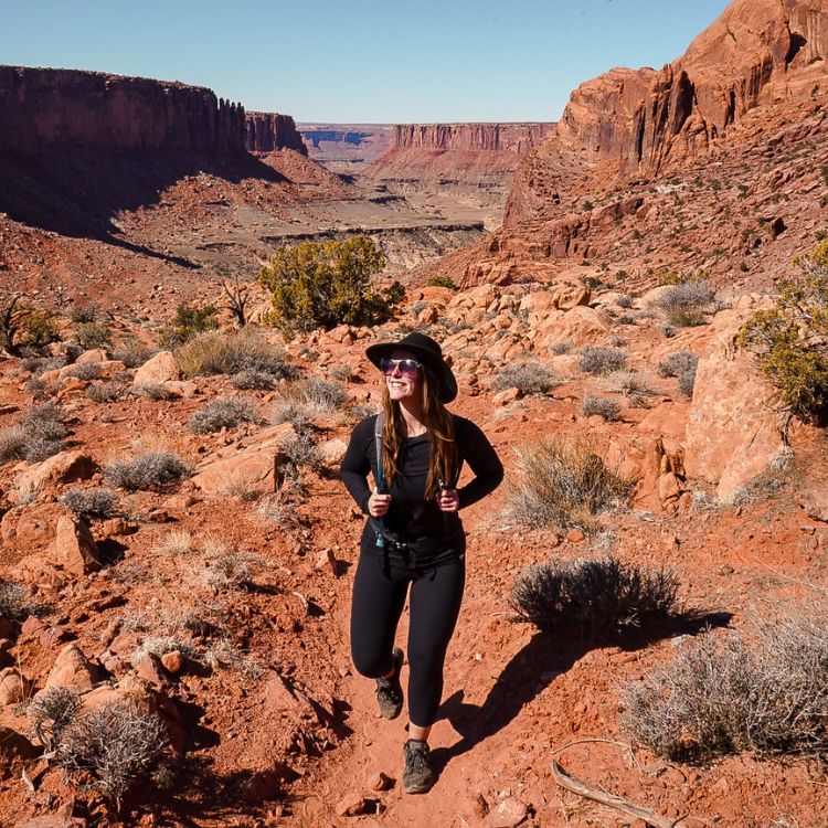 Woman wearing all black hikes the Syncline Loop in Canyonlands National Park.
