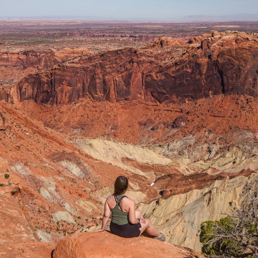 Woman sitting in Canyonlands National Park overlooking Upheaval Dome.