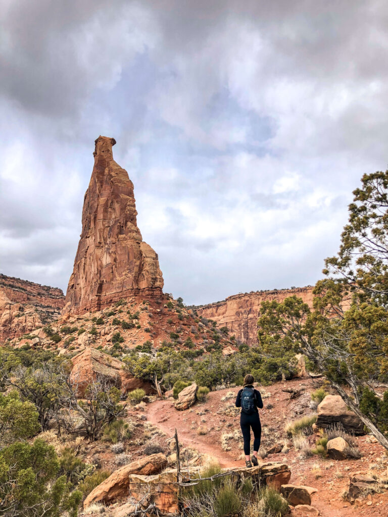 Woman stands on a rock looking at Independence Monument in Colorado National Monument.