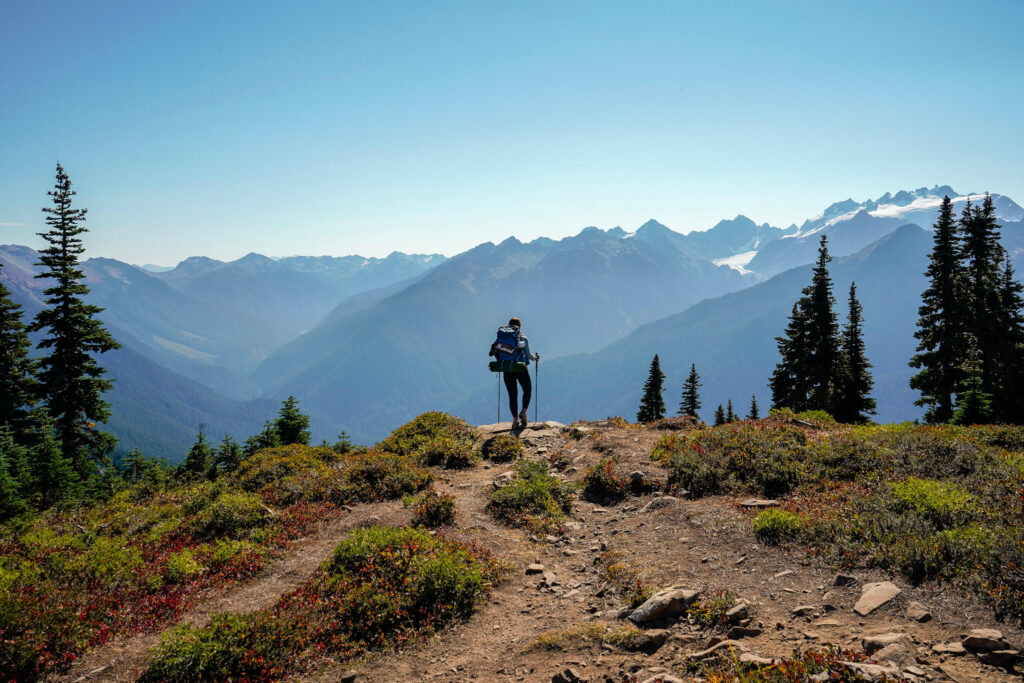 Woman backpacking in Olympic National Park on her honeymoon with snow-capped mountains in the distance.