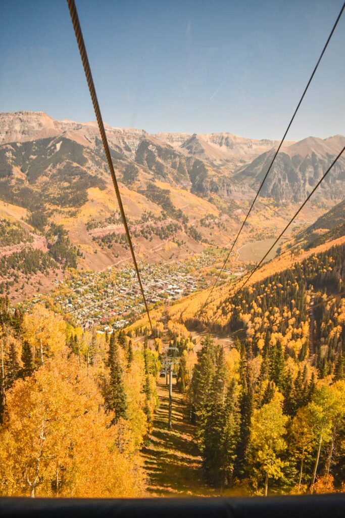 Looking out of the Telluride gondola over golden aspen trees and mountains.
