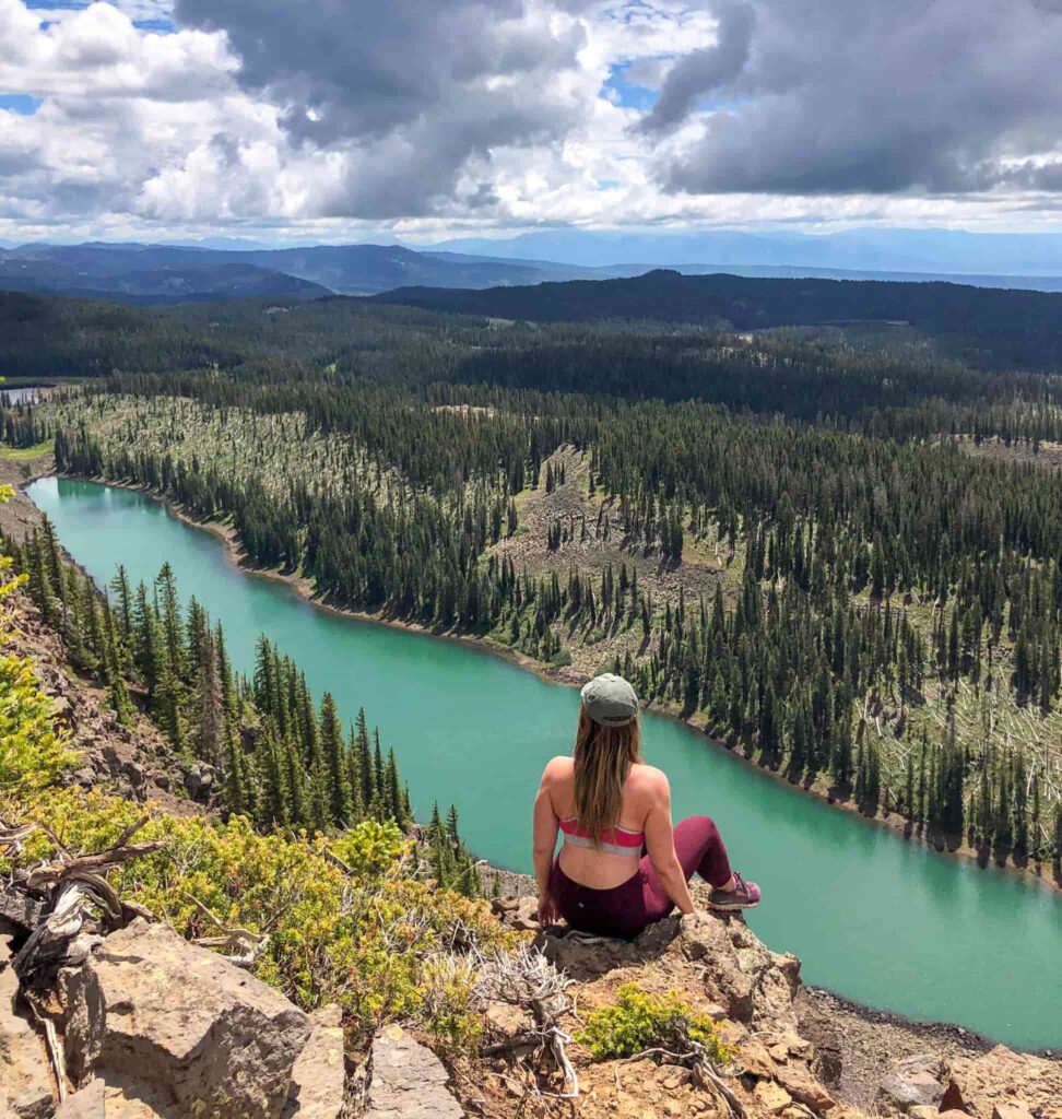 Woman sitting on a rock overlooking a blue lake on the Grand Mesa.