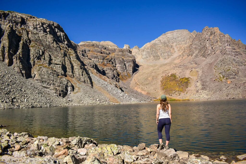 Woman standing next to an alpine lake near Aspen, Colorado.