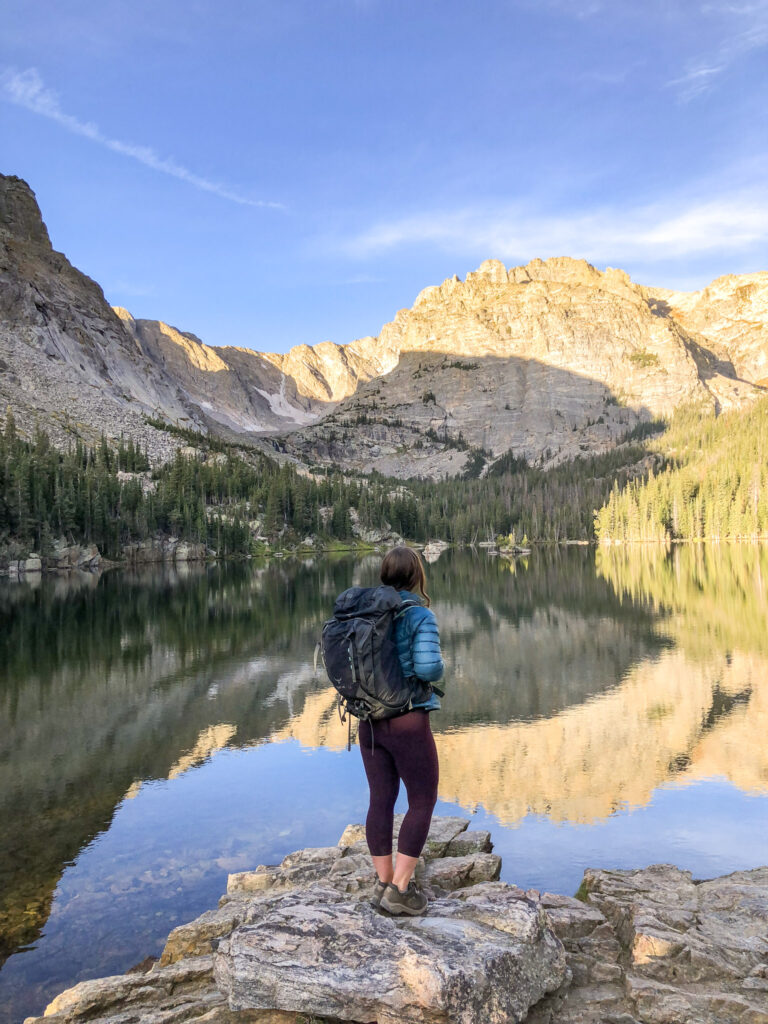 Woman hiking alone in Rocky Mountain National Park while carrying the 10 essentials in a large backpack.
