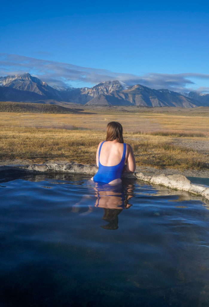 Woman in a blue bathing suit soaking in Hilltop Hot Springs near Mammoth Lakes, California.