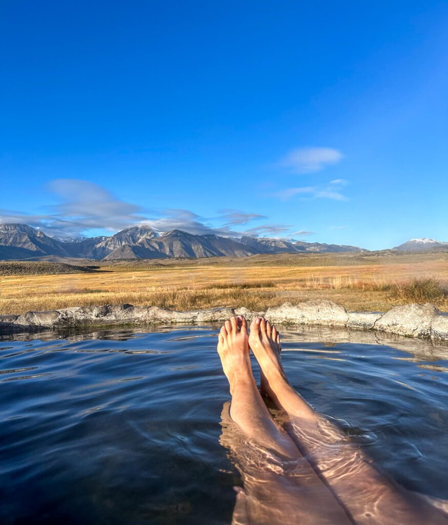 Soaking in Hilltop Hot Springs with feet in the air and a view of the Eastern Sierra mountains.