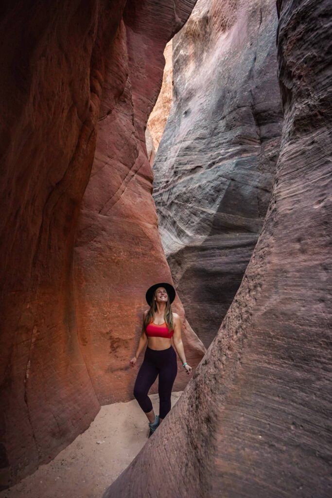 Woman looking up in a slot canyon while hiking in Southern Utah.