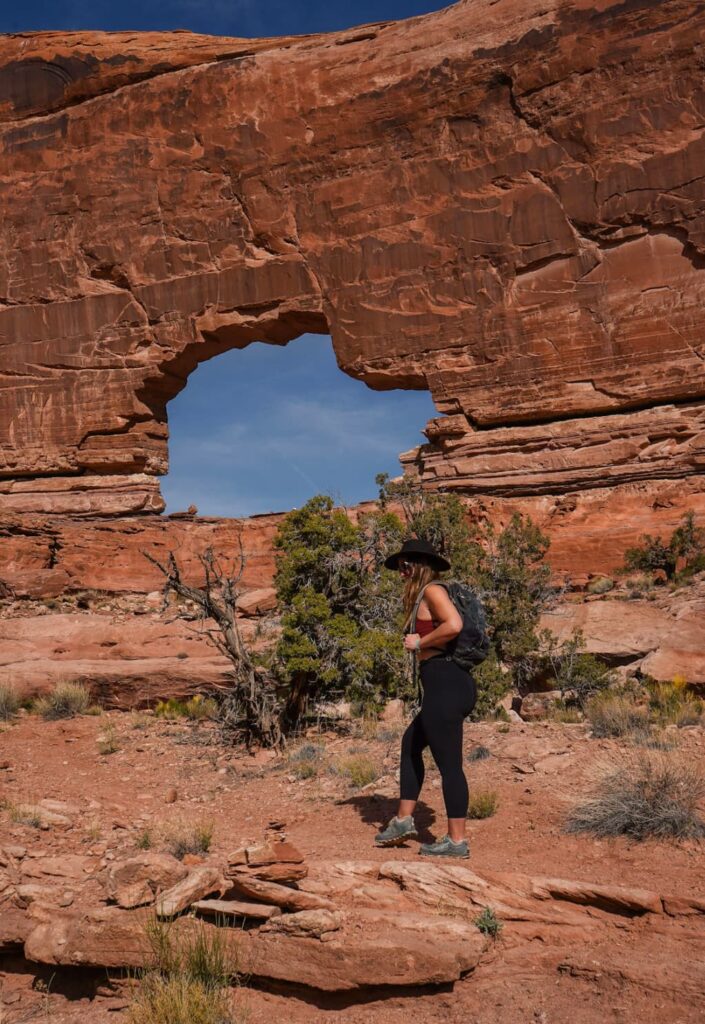 Woman hiking in front of Jeep Arch in Southern Utah.