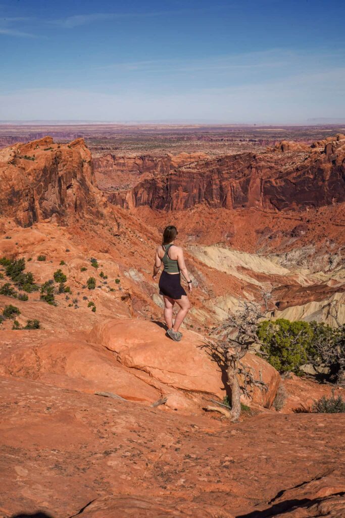 Woman stands on a rock overlooking the Upheaval Dome in Canyonlands National Park.