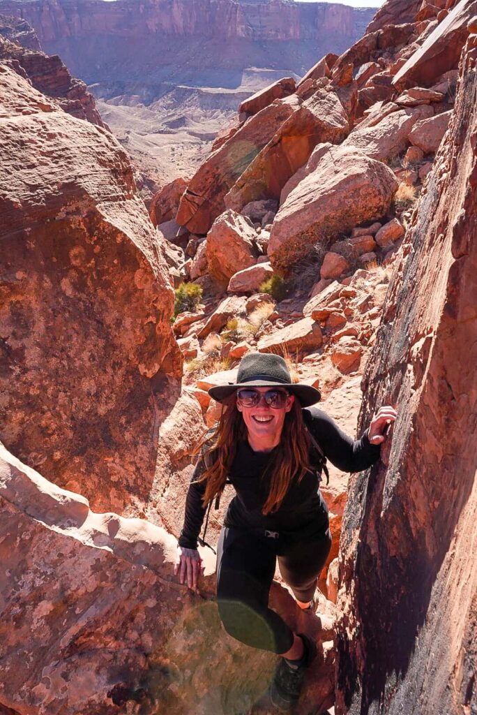 Woman scrambling through rocks while hiking in Southern Utah.