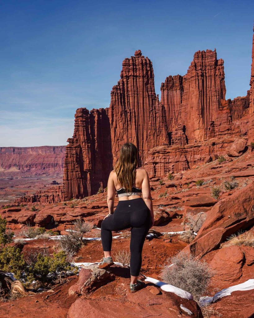 Woman standing in front of the Fisher Towers near Moab while hiking in Southern Utah.
