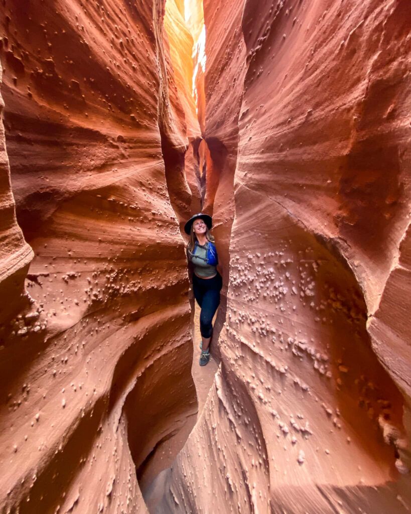 Woman stands in a red slot canyon in Southern Utah.
