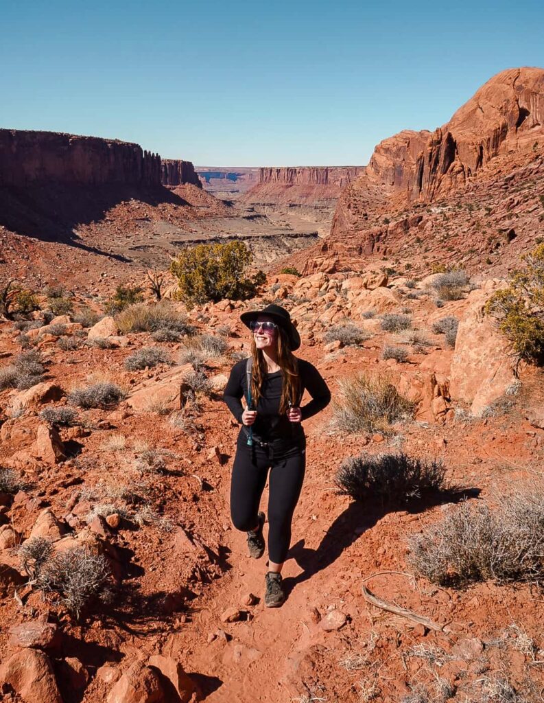 Woman wearing all black on a desert hiking trail in Canyonlands National Park.