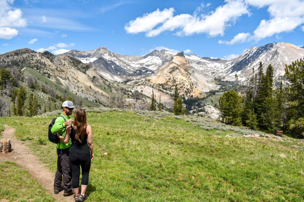 A couple standing on a hiking trail in front of mountains in Sun Valley, Idaho.