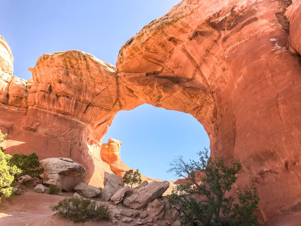 An arch that looks like 2 camels kissing with a blue sky in the background.
