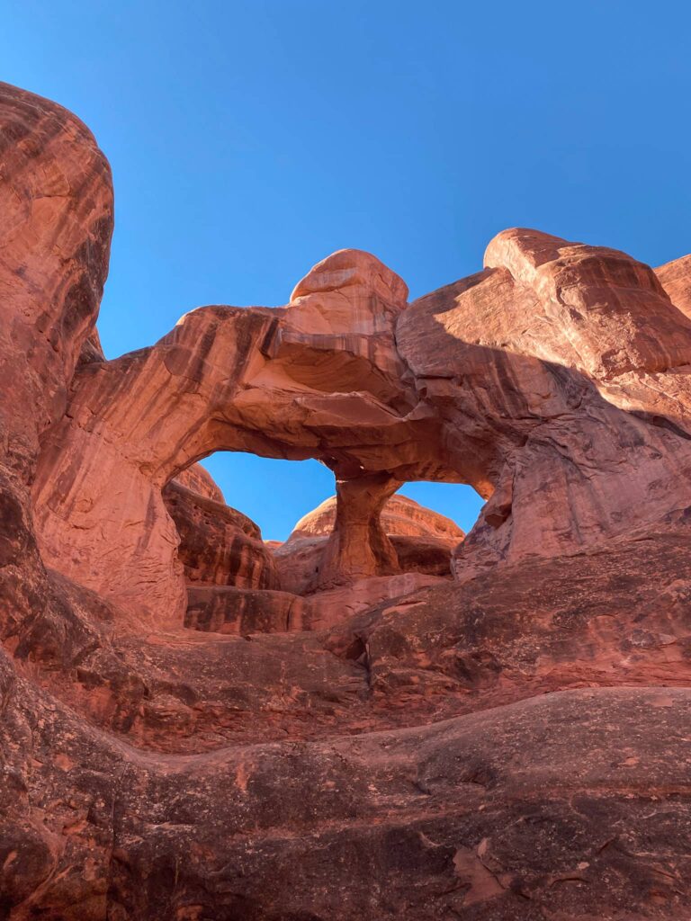 Skull Arch in Arches National Park with a blue sky in the background.