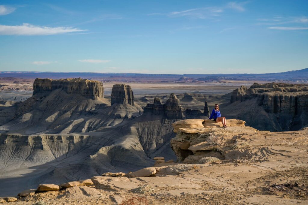 Woman sitting on a rock outcropping overlooking the Utah badlands around Hanksville, Utah at Moonscape Overlook.