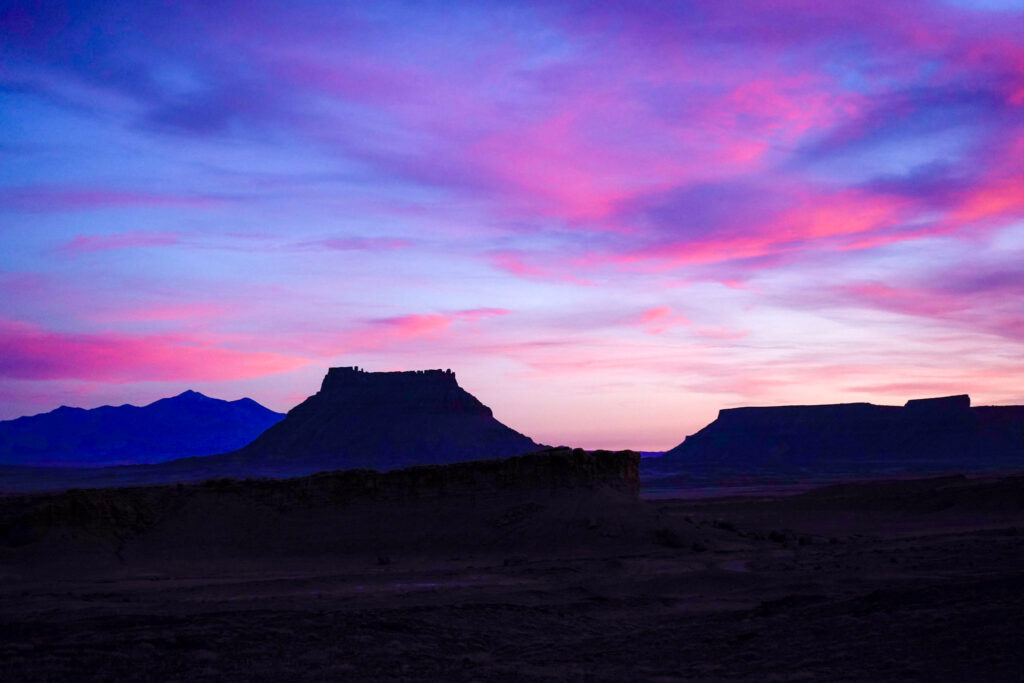 A pink and purple sunset over Factory Butte and the Henry Mountains outside of Hanksville, Utah.